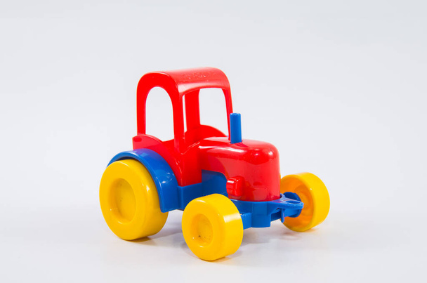 Пластиковый игрушечный трактор на белом фоне. - Фото, изображение