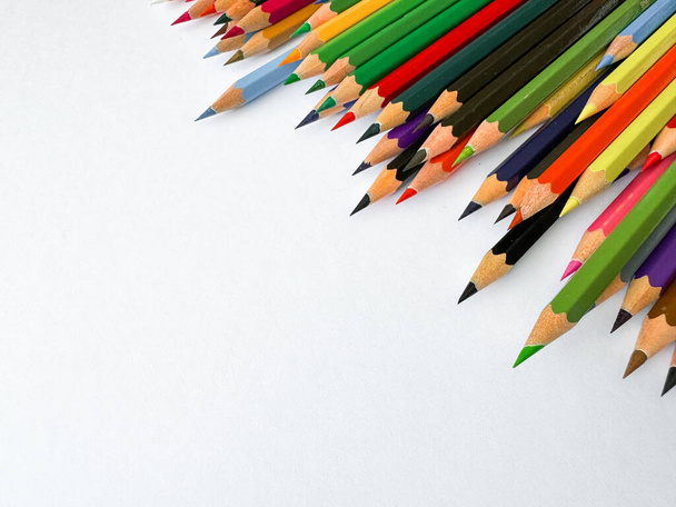 Diagonale Anordnung von scharfen Buntstiften auf weißem Hintergrund mit leerem Raum für Text. Künstlerisches Konzept für Schreibwaren, Bildung, Design oder Werbebanner für Schulprodukte. - Foto, Bild