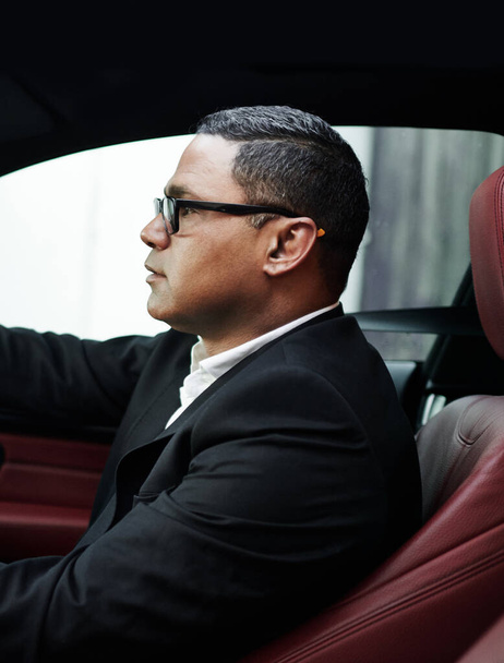 Profile, gentleman and entrepreneur in a luxury car, rich person and wealthy with morning commute and travel. Transportation, business and glasses with success and corporate professional with vehicle. - Photo, Image