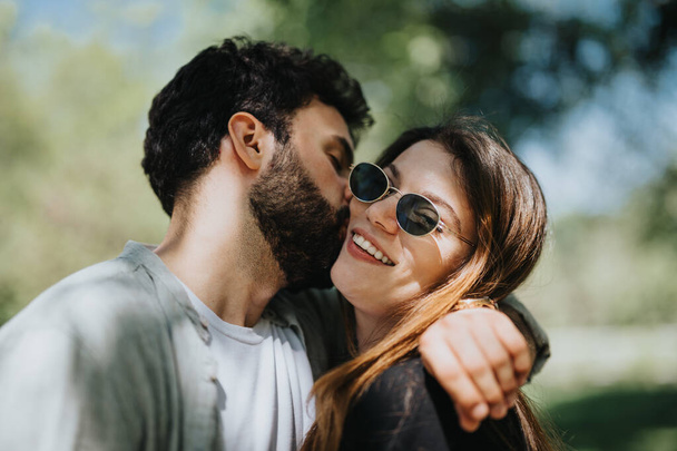 Ein unbeschwertes junges Paar genießt einen ungezwungenen, fröhlichen Moment, umarmt sich an einem sonnigen Tag in einem Stadtpark und strahlt Glück und Positivität aus.. - Foto, Bild