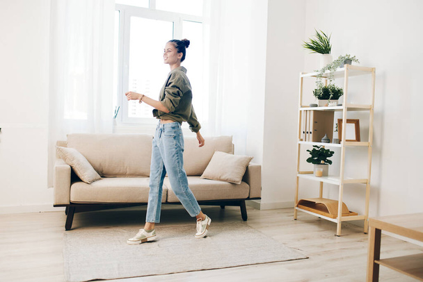 Joyful vrouw springen met muziek en geluk in ontspannen appartement - Foto, afbeelding