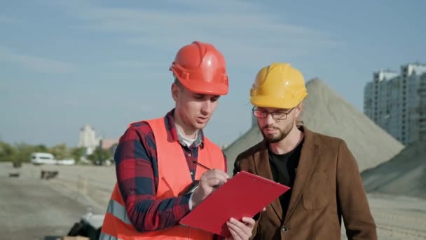 Professional male walking with foreman, discuss about work process, make notes on clipboard. Slow motion video - Footage, Video