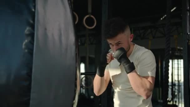Homme fort dans l'entraînement de gants de boxe avec sac de boxe dans le gymnase entraînement de boîte professionnelle sport athlète boxeur boxeur champion avec la puissance forte motivation frapper battre préparer pour le combat - Séquence, vidéo