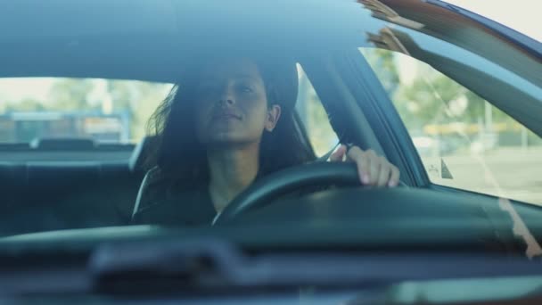 Glimlachende dame zit in de auto, rijdt en geeft signaal om te bewegen op de weg. Video in slow motion - Video