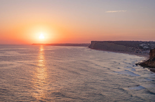 Ηρεμία ηλιοβασίλεμα στον ωκεανό με το φως του ήλιου αντανακλάται στο νερό. Λάγος, Πορτογαλία στις 10 Οκτωβρίου 2023. - Φωτογραφία, εικόνα