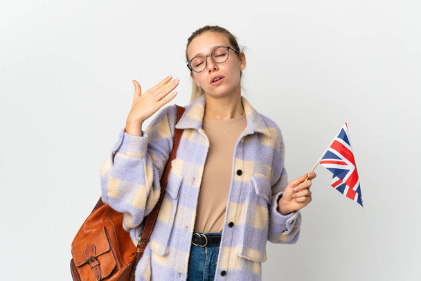 Mujer rubia joven sosteniendo una bandera del Reino Unido aislada sobre fondo blanco con expresión cansada y enferma - Foto, Imagen
