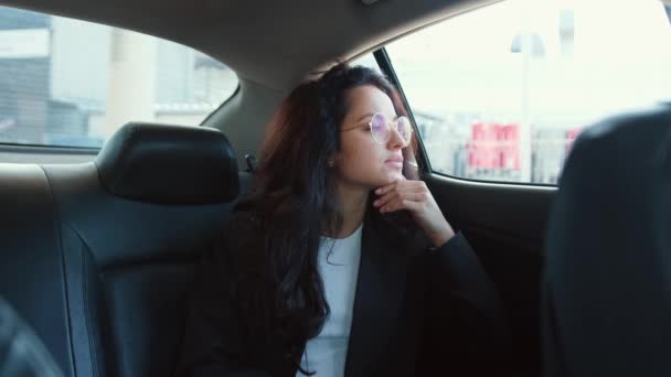 Mladá žena v brýlích sedí v autě, dívá se do okna a sní. Zpomalené video - Záběry, video