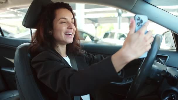 Vrouwelijke rijdende auto, met smartphone en praten op video. Video in slow motion - Video