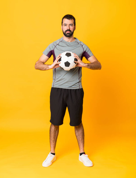 Ganzkörperaufnahme eines Fußballspielers vor isoliertem gelben Hintergrund - Foto, Bild