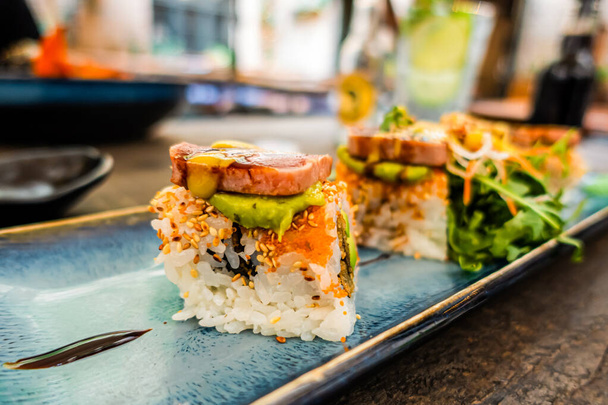 Widok na talerz sushi rolki. apetyczna rolka na niebieskim prostokątnym ceramicznym talerzu serwowana jest na stole w restauracji - Zdjęcie, obraz
