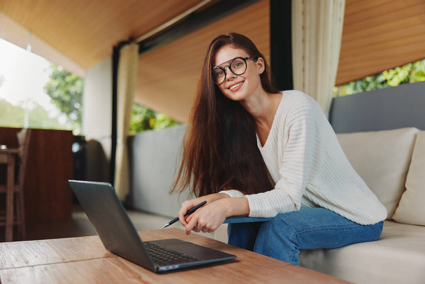 İnternetten Eğitim ve İş Konseptinde Dizüstü bilgisayarla Koltukta oturan Gülümseyen Kadın - Fotoğraf, Görsel