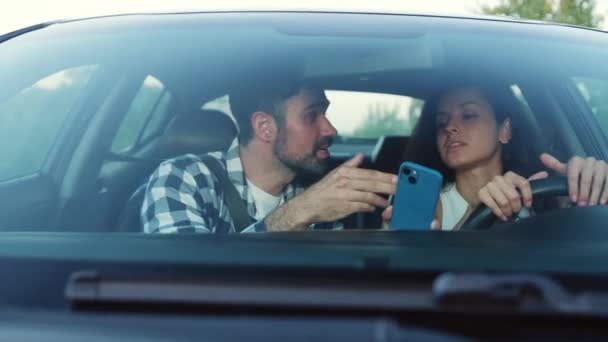 Mies selittää naiselle, miten päästä reittiä pitkin käyttämällä navigaattoria puhelimessaan. Kuljetus, matka, teknologia, ihmisten käsite. Hidastus - Materiaali, video