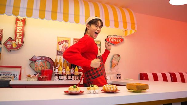 Szakmai ázsiai éttermi dolgozó elkészíti az ételt, és az ételbár mögött áll. Boldog pincér piros inggel és piros köténnyel mozgó freestyle zene közben a kamerába. Őrült tánc. Regnálás. - Fotó, kép