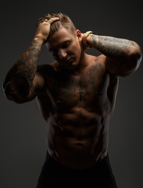 Muscular man with tattooes in deep shadows - Photo, Image