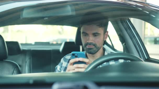 Conducteur souriant utilisant un téléphone portable tout en étant assis dans la voiture. Transport, technologie, mode de vie. Mouvement lent - Séquence, vidéo