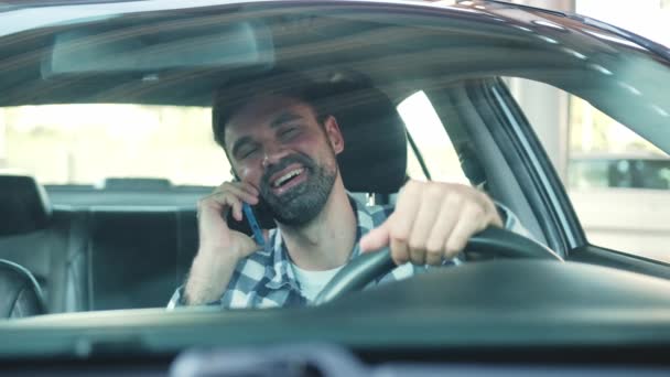 Усміхнений хлопець сидить у машині, розмовляючи по смартфону. Транспорт, технології, концепція способу життя. Повільний рух - Кадри, відео