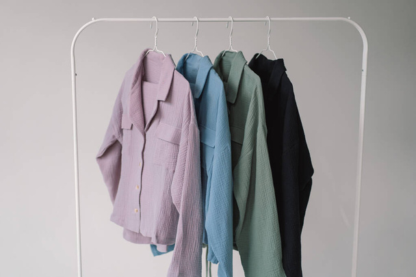 Uma coleção de roupas coloridas em tons variados de rosa claro a azul escuro é exibida em um rack de roupas de metal. - Foto, Imagem