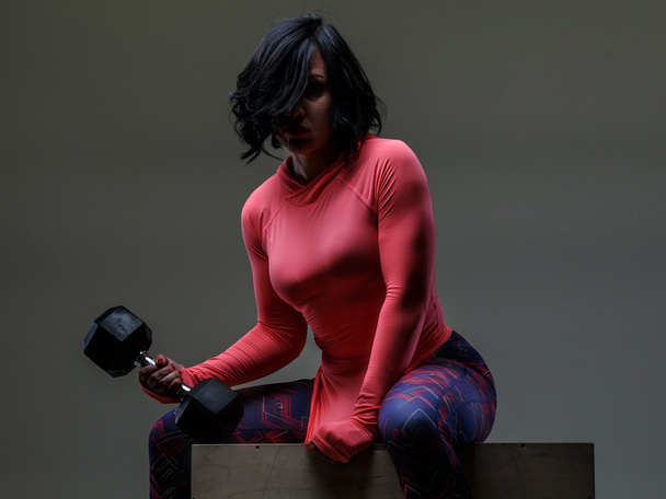 Woman with black hair holding dumbell - Photo, Image
