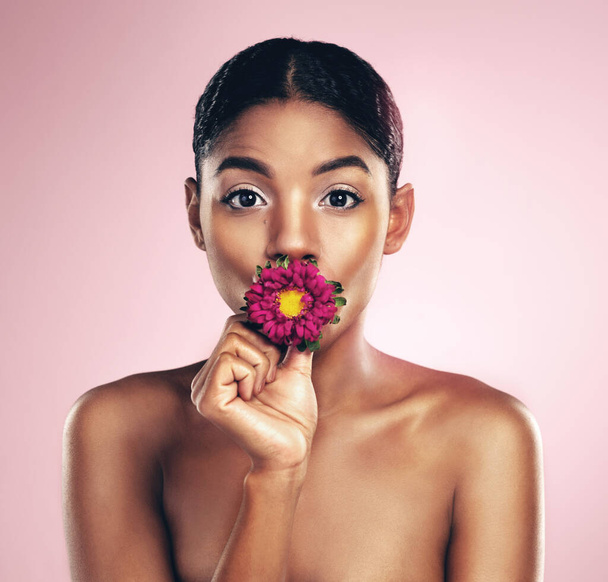 Woman, flower and portrait in studio for wellness with makeup on pink background for aesthetic or visual impact. Springtime, plant and eye with beauty, floral and blossom with clear skin with glow. - Photo, Image