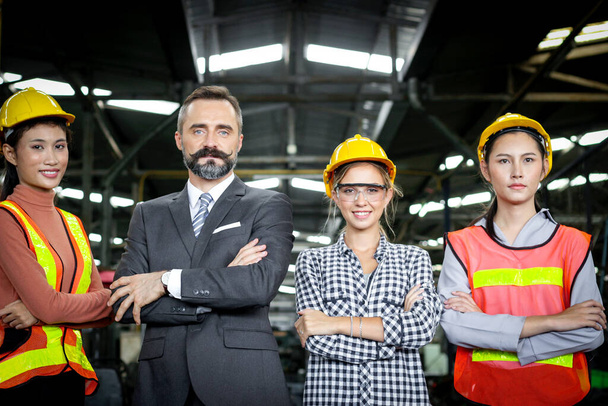Vezető üzletember menedzser ipari mérnök nőkkel, bukósisakkal a gyártóipari gyárban. Ipari dolgozók és főnökök csoportja keresztbe tett karokkal a munkahelyen. - Fotó, kép