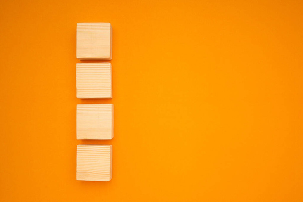 Vista superior de cuatro cubos de madera en blanco sobre un fondo amarillo con espacio para texto. - Foto, imagen