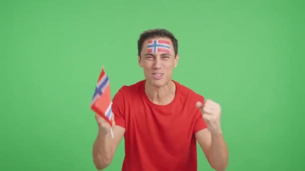 Wideo w studiu z chromą mężczyzny namiętnie dopingującego Norwegię krzyczącą i machającą flagą narodową - Materiał filmowy, wideo
