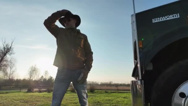 Amerikan yarı kamyonunun önündeki Kovboy Şapkalı Gururlu Kafkas Kamyoncu. Ön Manzara. Taşımacılık ve Ağır Görev Ulaşım TemasıName. - Video, Çekim