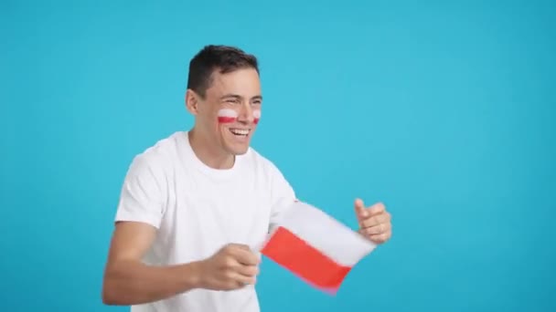 Video en estudio con el croma de un hombre animando a Polonia gritando y ondeando una bandera nacional, mirando hacia el espacio de copia en blanco - Imágenes, Vídeo