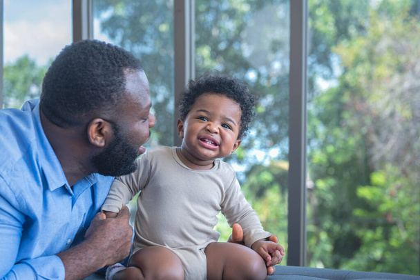 familia africana Un bebé nigeriano de 10 meses de edad está en la cama con su padre. sonreír y ser feliz con las relaciones familiares africanas y el concepto inocente de un niño pequeño - Foto, Imagen