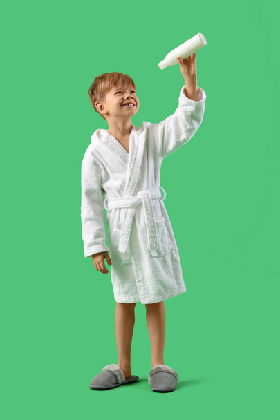 Симпатичный маленький мальчик в халате с гелем для душа на зеленом фоне - Фото, изображение