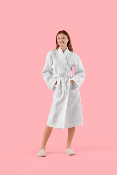 Beautiful young woman in bathrobe on pink background - Photo, Image