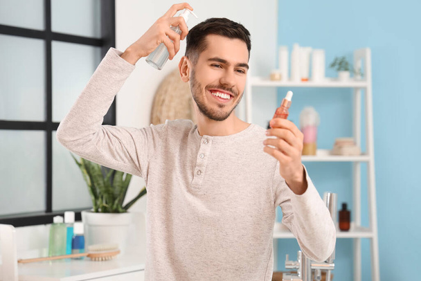 Jeune homme avec des produits pour la croissance des cheveux dans la salle de bain - Photo, image