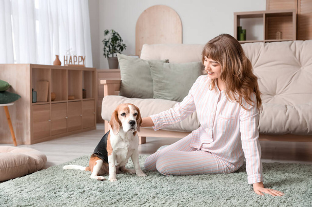 fiatal nő aranyos beagle kutya ül szőnyegen otthon - Fotó, kép