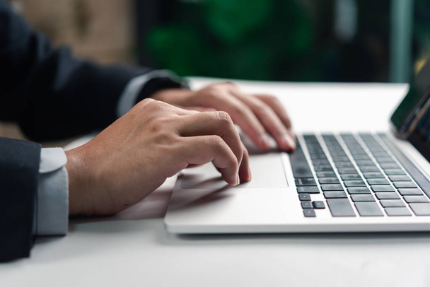 Профессионал бизнеса, работающий над ноутбуком, сосредоточен на задаче с размытым зеленым фоном - Фото, изображение
