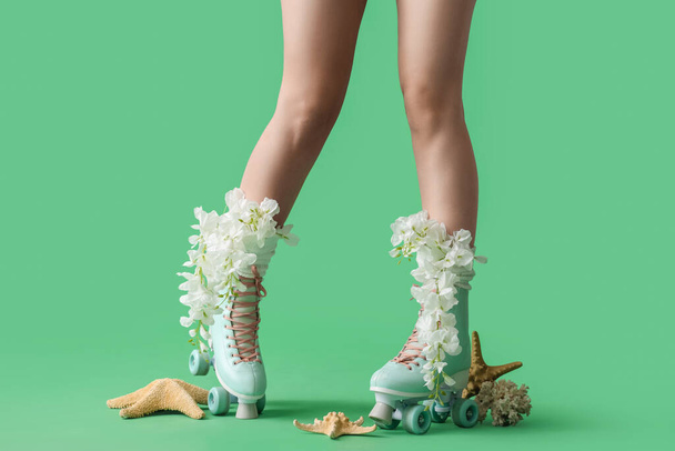 Yeşil arka planda patenli çiçeklerle güzel genç bayanların bacakları - Fotoğraf, Görsel