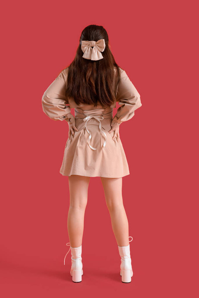 Стильна молода жінка з луками на червоному тлі, вид ззаду - Фото, зображення