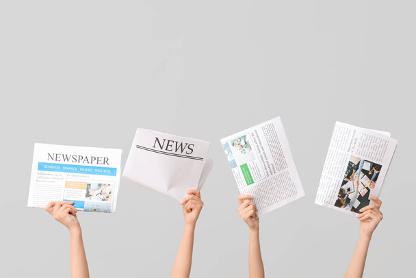 Mani femminili con giornali su sfondo grigio - Foto, immagini
