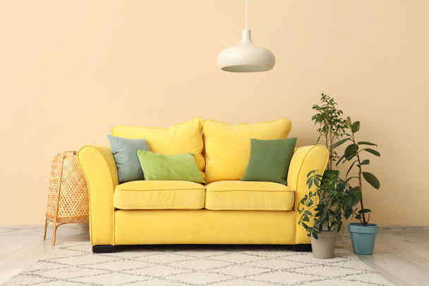 Интерьер бежевой гостиной с желтым диваном и комнатными растениями - Фото, изображение
