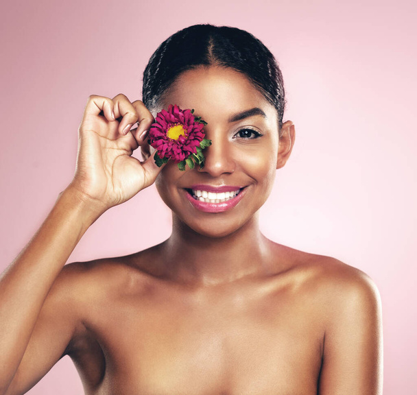 女性,スタジオ,そして目の上の花,化粧品,笑顔の自然な美しさの肖像画. アフリカの化粧,口紅,基礎のための花の女性モデル,幸福とピンクの背景. - 写真・画像