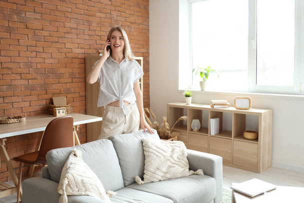 Mujer bonita joven hablando con el teléfono móvil en la sala de estar - Foto, Imagen