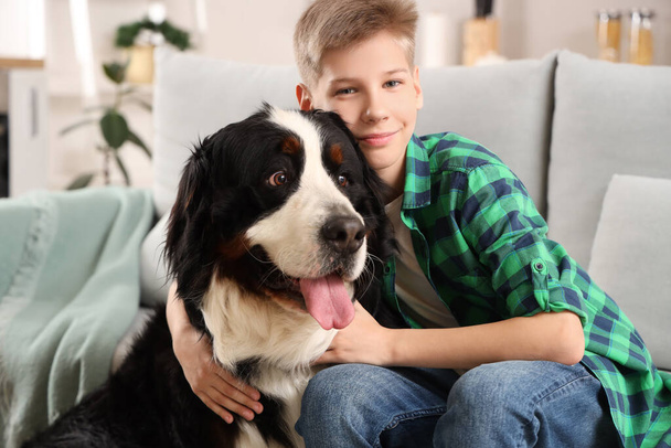 Αγόρι με χαριτωμένο χνουδωτό σκυλί κάθεται στον καναπέ στο σαλόνι - Φωτογραφία, εικόνα