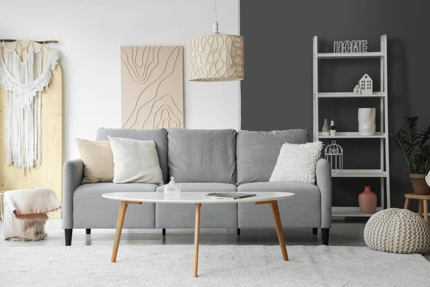Elegante interior de la sala de estar con sofá gris, mesa de centro y estantería - Foto, Imagen
