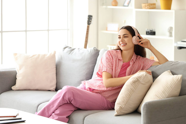 Gyönyörű fiatal, boldog nő fülhallgatóban zenét hallgat otthon - Fotó, kép