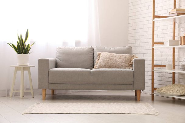 Интерьер стильной гостиной с серым диваном и светлыми шторами - Фото, изображение