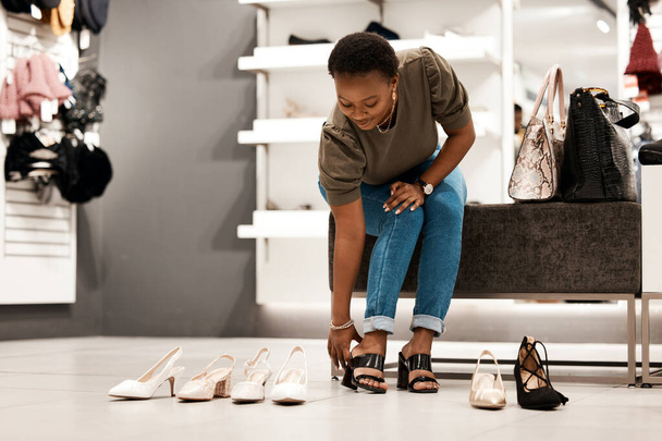 Detailhandel, zwarte vrouw en schoenen voor fashion shopping, klant en aankoop in de winkel. Promotie, winkelcentrum en product voor korting en boetiek of outlet, consument en kopen voor schoeisel of hoge hakken. - Foto, afbeelding