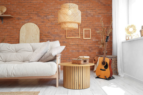Interieur eines schönen Wohnzimmers mit bequemem Sofa, Gitarre und Couchtisch - Foto, Bild