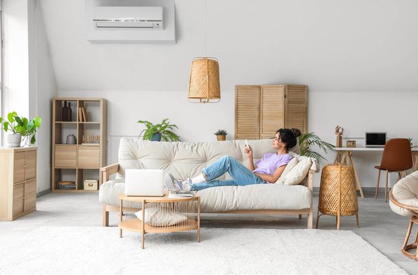 Jovem afro-americana ligando ar condicionado em casa - Foto, Imagem