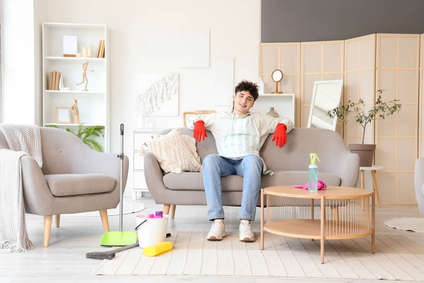 Young man sitting on sofa after cleaning at home - Photo, Image