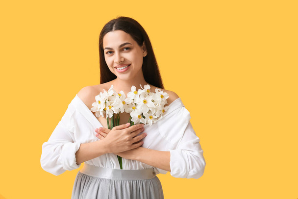 Onnellinen nuori nainen kukkakimppu valkoinen daffodil kukkia keltainen tausta - Valokuva, kuva
