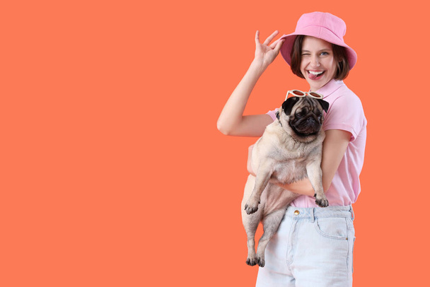 Young woman with cute pug dog on orange background - Photo, Image
